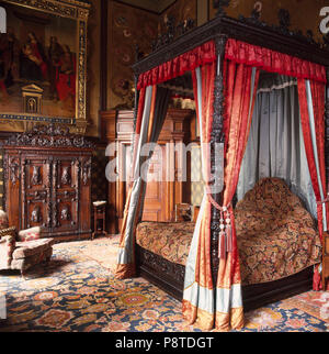 Lit à baldaquin avec des rideaux opulents et couvre-lit en maison de chambres avec des tapis orientaux Banque D'Images