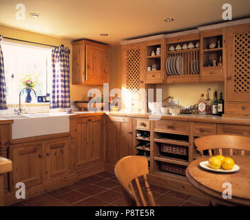 Blue +rideaux à carreaux blancs au-dessus de l'évier en céramique blanc en chalet cuisine avec placards en bois équipé Banque D'Images