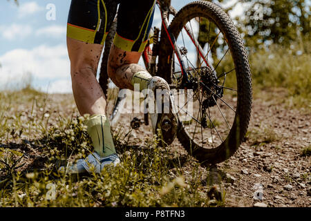 Retour pieds sales mountain biker grimpe la pente avec location Banque D'Images