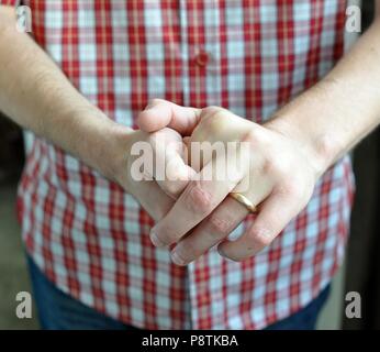 Un homme avec une chemise rouge à carreaux, la fissuration dans ses doigts de la main, front view, portrait, Close up Banque D'Images