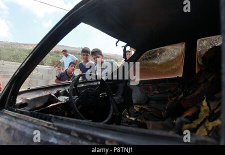 Naplouse, Urif village près de la ville cisjordanienne de Naplouse. Le 13 juillet, 2018. Les garçons palestiniens inspecter une voiture brûlée après les colons juifs y avaient mis le feu, à l'Urif village près de la ville cisjordanienne de Naplouse, le 13 juillet 2018. Plus tôt mardi, des sources palestiniennes ont indiqué que les colons à partir de la colonie de Yitzhar ont attaqué le village d'Urif près de Naplouse et brûlé deux voitures palestiniennes. Credit : Nidal Eshtayeh/Xinhua/Alamy Live News Banque D'Images