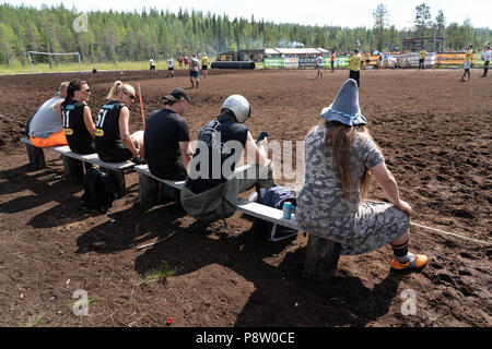 Hyrynsalmi, Finlande, 13 juillet 2018. Le Marais du monde de football 2018 en Hyrnsalmi à Ukkohalla. Environ 2000 concurrents prennent part chaque année dans le monde le marais le plus vieux tournoi de soccer. Sur la photo : l'action et des scènes de foule à partir de la première journée chaude de cloques. Les températures ont grimpé à près de 30 degrés et c'était très difficile pour les équipes et leurs fans. Photo : Rob Watkins/Alamy News Banque D'Images