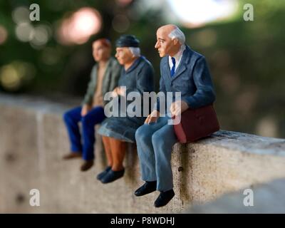 Univers miniatures sur un mur en bois. Miniatures figurines représentant des grands-parents et leur petit-fils assis et l'attente Banque D'Images