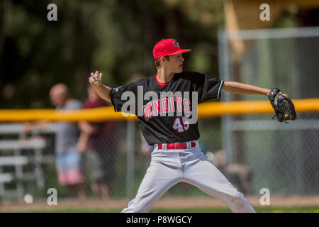 La prestation de Pitcher la hauteur, en pleine course, montrant l'adhérence, les garçons d'après-midi d'un match de baseball junior. Cranbrook, BC. Banque D'Images