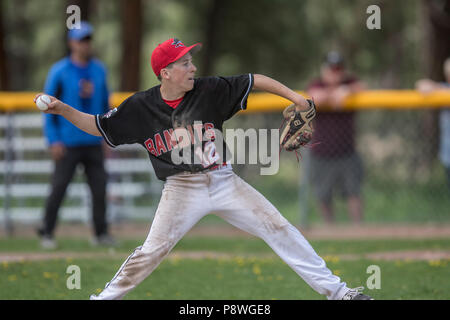 La prestation de Pitcher la hauteur, en pleine course, montrant l'adhérence, les garçons d'après-midi d'un match de baseball junior. Cranbrook, BC. Banque D'Images