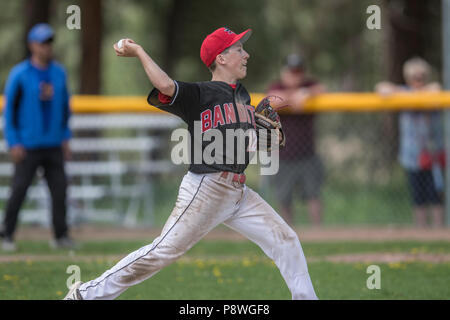 La prestation de Pitcher la hauteur, en pleine course, montrant l'adhérence, les garçons d'après-midi d'un match de baseball junior. Cranbrook, BC. Banque D'Images