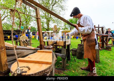 L'histoire vivante, une reconstitution d'un événement. L'homme médiéval, forgeron, à l'aide de soufflets et forge pour fabriquer le fer des armes. Banque D'Images