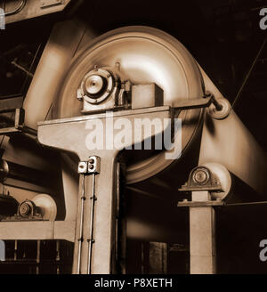 Film photographique tourné. Image en noir et blanc avec sépia et visible du grain de film d'un papel rolling batterie dans une ancienne usine. Banque D'Images