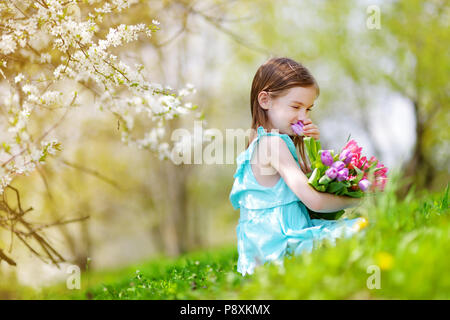 Adorable petite fille holding tulipes pour sa mère dans blooming cherry garden sur beau jour de printemps Banque D'Images