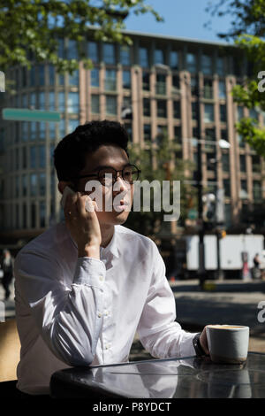Man taking on mobile phone at outdoor cafe Banque D'Images