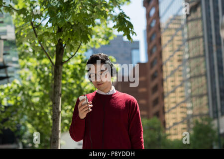 L'homme à l'écoute de la musique sur téléphone mobile om la rue Banque D'Images