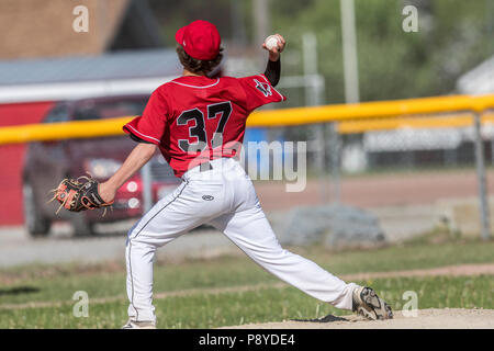 La prestation de Pitcher la hauteur, en pleine course, montrant l'adhérence, les garçons d'après-midi d'un match de baseball junior. Cranbrook, BC. Banque D'Images