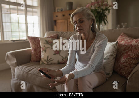 Senior woman with glucomètre contrôler le niveau de sucre dans le sang à la maison Banque D'Images