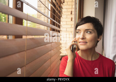 Woman talking on mobile phone in living room Banque D'Images