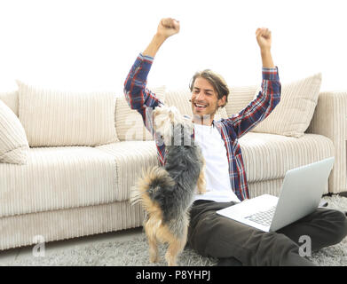 Heureux guy jubile avec son chien assis près du canapé dans le salon. Banque D'Images
