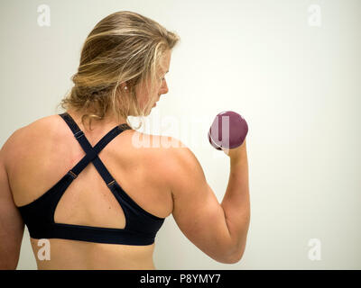 Strong female woman doing biceps pour l'exercice dans la salle de sport Banque D'Images