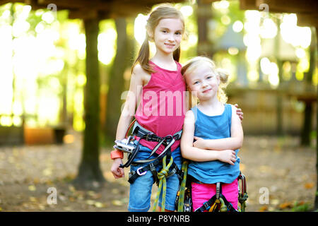 Deux adorables petites filles profitant de leur temps dans l'escalade parc aventure sur jour d'été chaud et ensoleillé. Activités d'été pour les jeunes enfants. Enfants havi Banque D'Images