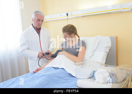 Médecin homme contrôle de la pression artérielle de la femme enceinte à l'hôpital Banque D'Images