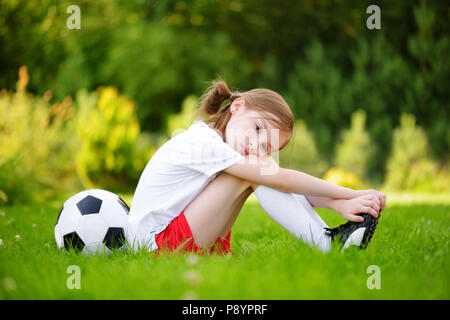 Mignon petit joueur de football ayant du plaisir à jouer un match de football aux beaux jours d'été. Activités sportives pour les enfants. Les enfants dans les sports uniforme. Banque D'Images