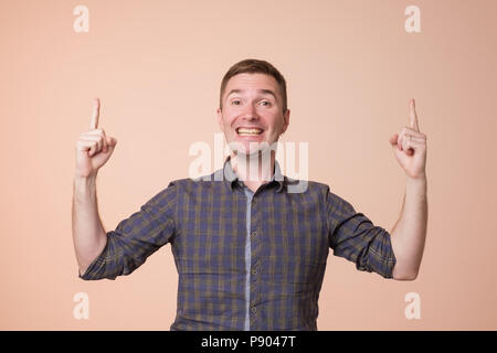 Surpris jeune homme pointant vers le haut avec deux mains. Hey look up concept Banque D'Images