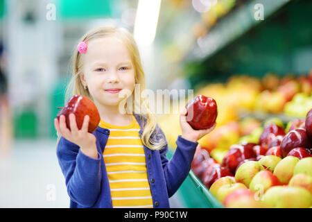 Petite fille Choisir des pommes mûres dans un magasin d'alimentation ou d'un supermarché Banque D'Images