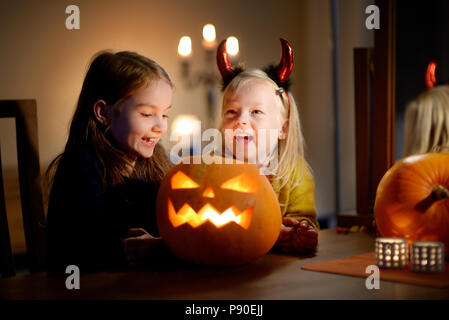 Deux jolies jeunes sœurs dans Halloween costumes sculpture d'un ensemble de citrouille à l'Halloween Banque D'Images