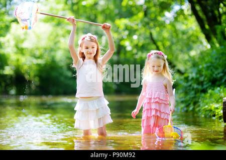 Deux mignonnes petites sœurs jouant dans une rivière capture de canards en caoutchouc avec leur scoop-filets de jour d'été chaud et ensoleillé Banque D'Images