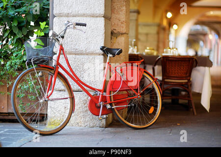 Vélo rouge branché garée dans une rue de la ville de Desenzano del Garda, Italie Lombardie Banque D'Images