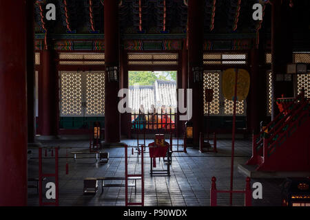 Trois jeunes filles vêtues de robes traditionnelles coréennes se profilent à une fenêtre dans la salle du trône dans le Palais de Gyeongbokgung, Séoul, Corée du Sud. Banque D'Images