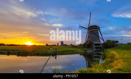 Trois moulins à vent en bois néerlandais historique au coucher du soleil dans les polders néerlandais Banque D'Images
