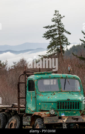 PIRIN, BULGARIE - Mars 17, 2018 : vert Vintage vieux camion Praga, bulgare plaque est laissé à l'abandon à la rouille à l'extérieur dans une ferme de montagne. Nuageux springti Banque D'Images