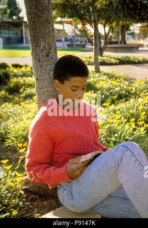 Teenage boy reading sous l'ombre des arbres, M. Pearson © Myrleen... Ferguson cate Banque D'Images