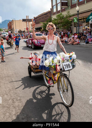 Femme à vélo tirant fils en wagon dans défilé annuel Quatrième de juillet dans la petite ville de montagne de Salida, Colorado, USA Banque D'Images