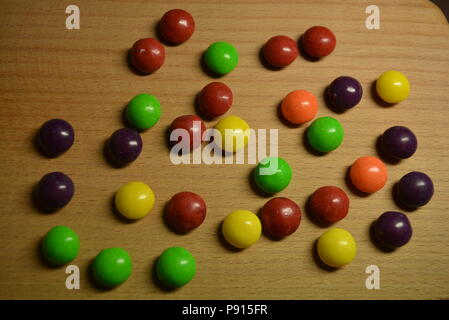 Délicieux bonbons, secouer le bonbon violet, jaune, rouge, orange et vert clair sur un fond en bois. Banque D'Images