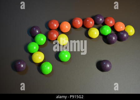 Délicieux bonbons, secouer le bonbon violet, jaune, rouge, orange et vert clair sur un fond mat. Banque D'Images