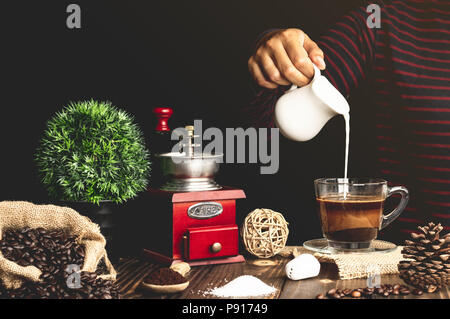 Café avec lait couler en verre sur un sol en bois Banque D'Images