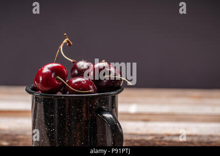 Les cerises mûres fraîches. Les cerises dans la tasse sur la table en bois laqué Banque D'Images