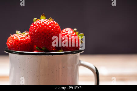 Petits fruits frais mûrs. Des fraises dans la tasse sur la table en bois Banque D'Images