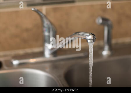 L'eau qui sort d'un robinet. Vue est une vue de 3/4 avec une faible profondeur de champ sur l'eau. Banque D'Images