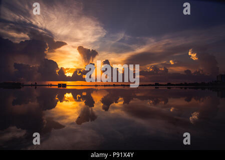 Fort Myers Beach pendant un coucher de soleil. Le ciel se reflète sur une grande flaque qui accumalates sur la plage lorsqu'il pleut. Banque D'Images