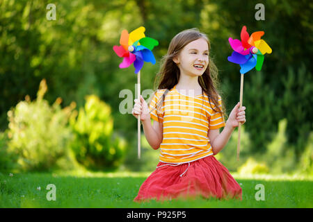 Adorable petite fille holding pinwheel jouet coloré sur jour d'été chaud et ensoleillé Banque D'Images