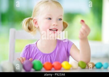 Cute little girl s'amusant avec de la pâte à modeler colorée dans une garderie. Creative kid molding à la maison. Enfant jouer avec la pâte à modeler ou de la pâte. Banque D'Images