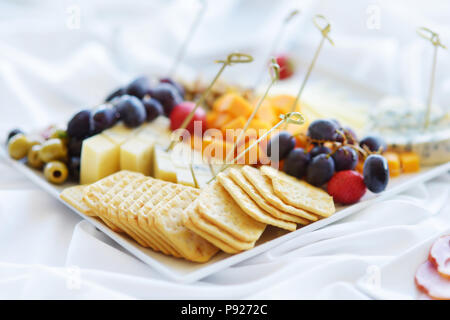 Différents types de vin en-cas : fromages, baguettes, biscuits, fruits et olives de table blanc Banque D'Images