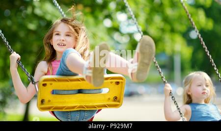 Deux mignonnes petites filles s'amuser sur une aire de jeux en plein air sur chaude journée d'été Banque D'Images