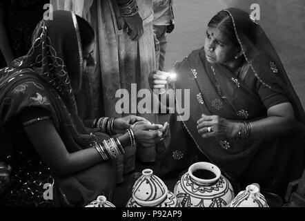 Les femmes du Rajasthan placer une bougie dans un pot en argile dans le cadre du festival à JOHDPUR GANGUR - RAJASTHAN, INDE Banque D'Images