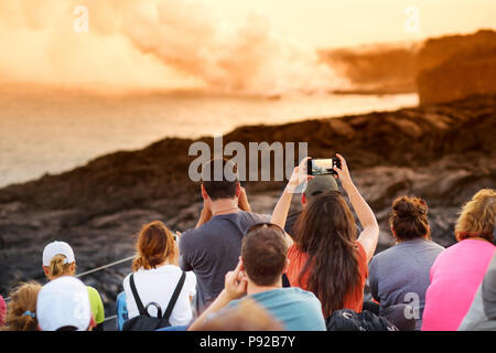 Les touristes de prendre des photos à Kalapana lava zone d'affichage. La coulée de lave dans l'océan créant un énorme nuage de fumée toxique à l'Hawaii Kilauea Volcano Banque D'Images