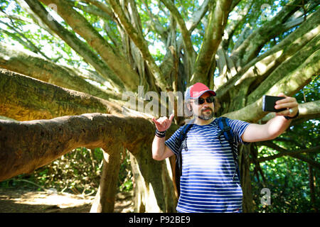 De tourisme de sexe masculin lui-même près de l'arbre banyan géant sur Hawaii. Branches et racines de pendaison arbre banyan géant sur l'île de Maui, Hawaii, USA Banque D'Images