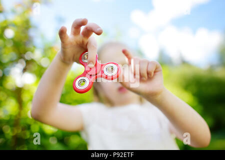 Cute school girl Playing with colorful fidget spinner sur l'aire de jeux. Populaires jouet anti-stress pour l'école les enfants et les adultes. Banque D'Images