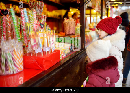 Cute Little Sisters le choix des bonbons sur le marché de Noël traditionnel pour les froides journée d'hiver. Les enfants d'acheter des bonbons et biscuits le jour de Noël. Banque D'Images