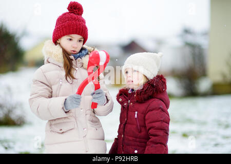 Deux adorables petites filles s'amusant avec bouilloire boule dans le magnifique parc d'hiver. Belles Soeurs jouant dans une neige. Activités d'hiver pour les enfants. Banque D'Images